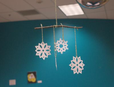 Image of paper snowflake, yarn, and stick mobile