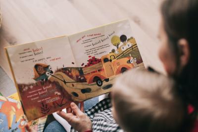 Mother reading book with young child in her lap.